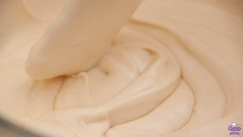 Brown sugar cream cheese frosting zoomed in photo with a spatula mixing the frosting. 
