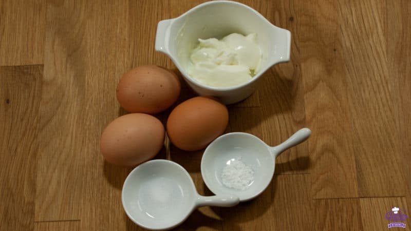 Ingredients for cloud bread recipe: yogurt, eggs, baking powder and salt. Pictured on a wooden surface.